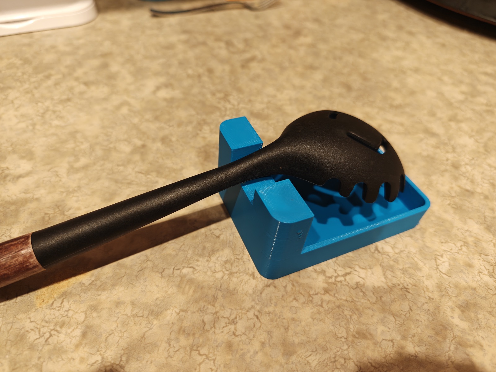 Blue drip tray holding a spatula on a kitchen counter